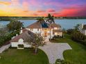 Stunning waterfront estate with lush landscaping, a brick driveway, and gorgeous sunset views at 429 St Andrews Dr, Belleair, FL 33756