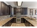 Modern kitchen featuring granite countertops, dark wood cabinets, stainless steel appliances, and tile backsplash at 8518 Broken Willow Ct, Tampa, FL 33647