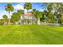 Expansive backyard with lush green lawn, white picket fence, and mature palm trees at 8717 Betty St, Port Richey, FL 34668