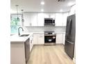 Modern kitchen featuring stainless steel appliances, white cabinetry, and marble countertops at 9830 Sheryl Dr, New Port Richey, FL 34654