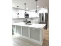 Bright kitchen boasts white cabinets, stainless steel appliances, and a large island with marble countertops at 9830 Sheryl Dr, New Port Richey, FL 34654