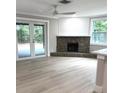 Spacious living room with a stone fireplace, wood beam accents, and sliding glass doors at 9830 Sheryl Dr, New Port Richey, FL 34654
