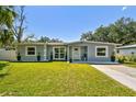 Charming single-story home with well-maintained lawn and landscaping in front at 6914 N Ola Ave, Tampa, FL 33604