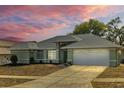 Inviting single-story home featuring a large driveway, two-car garage, and verdant landscaping at 1247 Venetia Dr, Spring Hill, FL 34608