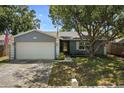 Charming one-story home with mature trees, a two-car garage, and landscaping at 1393 Chesterfield Dr, Dunedin, FL 34698
