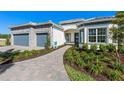 Charming home exterior featuring a two-car garage, paved walkway, manicured landscaping, and modern architectural design at 1845 Ridgemore St, North Port, FL 34289