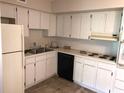 Well-lit kitchen with white cabinets, tile flooring, and functional appliances at 2450 Canadian Way # 6, Clearwater, FL 33763