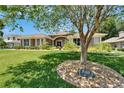 Landscaped front yard featuring mature tree and brick-lined garden bed displaying home address at 3060 Sutton Woods Dr, Plant City, FL 33566