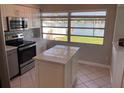 Bright kitchen featuring stainless steel appliances, an island, and large window with a water view at 419 12Th Ave, Indian Rocks Beach, FL 33785