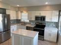 Modern kitchen featuring stainless steel appliances, an island, white cabinets, and stylish tile backsplash at 419 12Th Ave, Indian Rocks Beach, FL 33785