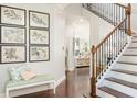 Inviting foyer with hardwood floors, a staircase with ornamental iron railings, and a bench beneath botanical wall art at 4204 W San Juan St, Tampa, FL 33629