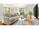 Bright living room featuring a neutral sofa, tropical wallpaper accent, and natural light through the sliding glass door at 4215 E Bay Dr # 1806D, Clearwater, FL 33764