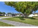 Exterior of home featuring a lush green lawn and a large shade tree in front at 8431 52Nd N Way, Pinellas Park, FL 33781
