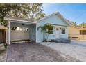 Charming light blue home featuring a quaint front yard and a convenient covered carport with brick driveway at 110 Kenwood Ave, Clearwater, FL 33755