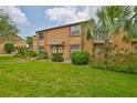 Charming two-story townhome with a well-manicured lawn, lush landscaping, and a beautiful palm tree at 1883 Clearbrooke Dr, Clearwater, FL 33760
