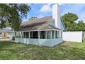 Back of the home featuring a enclosed patio and a white chimney with a well maintained lawn at 3093 Woodpine Cir, Sarasota, FL 34231