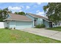 Front exterior of the home featuring a two-car garage, well maintained lawn and landscaping, and light blue paint at 3093 Woodpine Cir, Sarasota, FL 34231