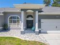 Charming front entrance with pillars, a gray tiled walkway, and double doors offers appealing curb appeal at 4951 Musselshell Dr, New Port Richey, FL 34655