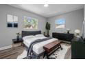 Serene main bedroom with calming gray tones, wood floors, a plush bed, and natural light from two windows at 660 Palm Ave, Tarpon Springs, FL 34689