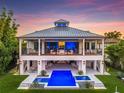 Beautiful home back exterior with a large pool, bar, patio, and manicured lawn at dusk at 721 Brightwaters Ne Blvd, St Petersburg, FL 33704