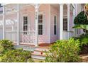 Close up on a beautiful front porch with pink siding, white pillars and manicured landscaping at 916 Hemingway Cir, Tampa, FL 33602
