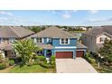 Aerial view of blue home with a brown roof, lush landscaping, and a spacious driveway at 10017 Smarty Jones Dr, Ruskin, FL 33573
