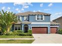 Lovely two-story home painted blue with a three-car garage, elegant entrance, and lush green landscaping at 10017 Smarty Jones Dr, Ruskin, FL 33573