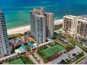 Aerial view showcasing the beachfront condo, swimming pool, tennis courts, and manicured landscaping at 1520 Gulf Blvd # 404, Clearwater, FL 33767