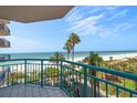 Balcony view featuring turquoise railings, beach scenery, and tropical palm trees at 1520 Gulf Blvd # 404, Clearwater, FL 33767