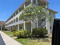 Inviting condo building featuring multiple floors, lush landscaping, and a charming tree with yellow flowers at 2434 Australia E Way # 22, Clearwater, FL 33763