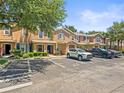 A row of tan townhomes with well-manicured lawns, a street lined with parked vehicles, and a beautiful, blue sky at 2529 Harn Blvd # 2, Clearwater, FL 33764