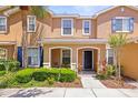 Tan two-story townhome with blue shutters, a palm tree, and a charming, covered front porch at 2529 Harn Blvd # 2, Clearwater, FL 33764