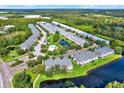 An aerial view of townhomes with a pond, community pool, parking, and lush landscaping at 26514 Chimney Spire Ln, Wesley Chapel, FL 33544