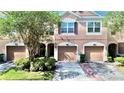 Beautiful townhome showcasing a private garage, arched entryway, and meticulously kept landscaping at 26514 Chimney Spire Ln, Wesley Chapel, FL 33544