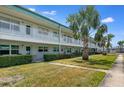 Exterior of this two-story condo featuring a lush green lawn, beautiful palm trees, and covered patios at 5267 81St N St # 8, St Petersburg, FL 33704