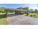 Wide view of a home with a spacious driveway leading to a covered garage, surrounded by a green lawn at 592 Ken Hubbard Rd, Terra Ceia, FL 34250