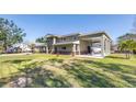 Side view of a two-story home featuring an attached boat carport and well-maintained lawn, complemented by a clear blue sky at 592 Ken Hubbard Rd, Terra Ceia, FL 34250