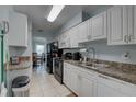 Galley kitchen with white cabinets, stainless appliances, and tile flooring at 8358 Candlewood Rd, Seminole, FL 33777