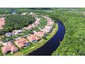 Overhead view of a neighborhood showcasing tile-roofed houses along a waterway surrounded by green landscape at 8474 Dunham Station Dr, Tampa, FL 33647