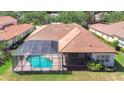 Aerial view of the private screened-in pool and backyard, nestled behind a single-story residence with a terracotta roof at 8474 Dunham Station Dr, Tampa, FL 33647