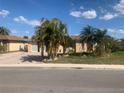 Cozy single-story house featuring an attached garage and mature palm trees in the front yard on a clear, sunny day at 9900 Island Harbor Dr, Port Richey, FL 34668