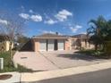 A single-story home with an attached garage and a large driveway, set under a bright blue sky with scattered clouds at 9900 Island Harbor Dr, Port Richey, FL 34668
