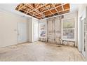Living room needing repair, featuring exposed ceiling beams, windows, a door, and damaged walls and floor at 18017 Villa Creek Dr # 18017, Tampa, FL 33647