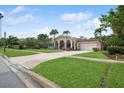 Inviting home featuring a brick driveway, lush lawn, and tropical landscaping, showcasing its exterior charm at 206 Corbett St, Belleair, FL 33756