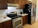 Efficient kitchen featuring stainless steel appliances, wooden cabinets, and tile floors at 2154 Briarway Dr, Clearwater, FL 33763