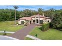 Elegant home boasts a paver driveway, manicured lawn, and stately palm trees on a sunny day at 2680 Keystone Springs Rd, Tarpon Springs, FL 34688