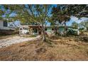 Charming home featuring a light green exterior, wooden pergola and a mature tree in front at 3962 Poinsettia Dr, St Pete Beach, FL 33706