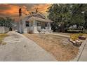 Side view of the charming white house with a brick chimney, driveway, and mature landscaping at 4519 5Th S Ave, St Petersburg, FL 33711