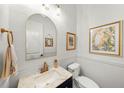 Chic powder room with an arched mirror, marble countertop and white tiling is stylish at 4804 W Beachway Dr, Tampa, FL 33609
