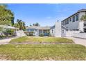 Charming light blue home featuring well-kept lawn, stone chimney, and gated entrance at 621 85Th N Ave, St Petersburg, FL 33702